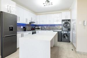 a kitchen with white cabinets and a black refrigerator at Shanthi Apartment 2 in Ballito