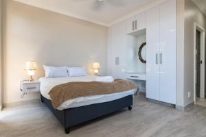 a white bedroom with a large bed and two lamps at Shanthi Apartment 2 in Ballito +25 photos
