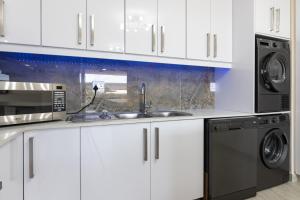 a kitchen with white cabinets and a sink and a microwave at Shanthi Apartment 2 in Ballito