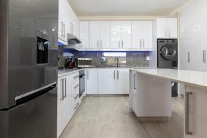 a kitchen with white cabinets and a stainless steel refrigerator at Shanthi Apartment 2 in Ballito