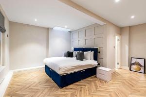 een slaapkamer met een bed met een blauw hoofdeinde bij Beautiful Two Bedroom Abode in Notting Hill in Londen
