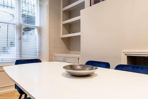 een witte tafel met stoelen en een kom erop bij Beautiful Two Bedroom Abode in Notting Hill in Londen