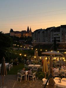 um grupo de pessoas sentadas a mesas num jardim à noite em La Fontaine em Hunedoara