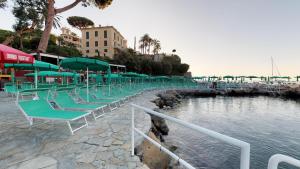 a group of chairs and umbrellas next to a body of water at Hotel Metropole in Santa Margherita Ligure