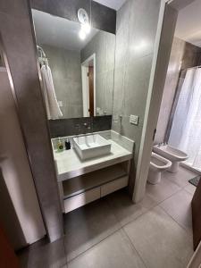 a bathroom with a sink and a toilet and a mirror at Em Departamento Amoblado Cordoba in Córdoba