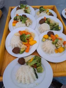 a tray of plates of food with rice and vegetables at Miskaa Nubian House in Naj‘ Tinjār