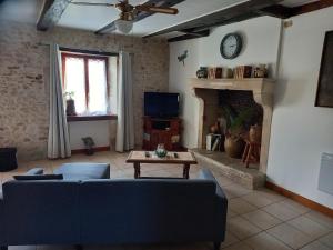 Una sala de estar con un sofá y una chimenea. en Le Papillon, en Savigné