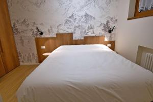 een groot wit bed in een slaapkamer met een muurschildering van de bergen bij SWEET Alps Apartment CCM in Madonna di Campiglio