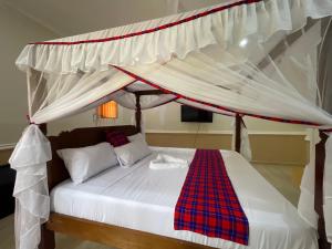 a bedroom with a bed with a canopy at Maasai Koroga in Mombasa