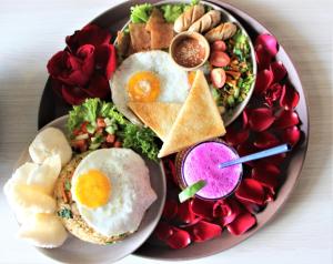 a plate of food with eggs and a salad and a drink at Reynten Hill Resort in Nusa Penida