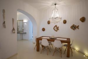 comedor con mesa, sillas y lámpara de araña en Thalasses Villas, en Kalafatis