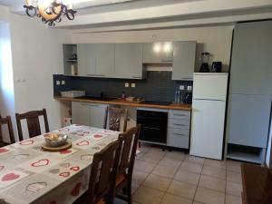Una cocina con una mesa y un refrigerador blanco. en Le Papillon, en Savigné