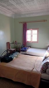 2 große Betten in einem Zimmer mit Fenster in der Unterkunft hôtel hicham in Ouarzazate
