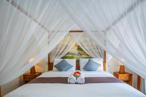 a bedroom with two beds with white drapes at Karang Island Villa in Nusa Lembongan