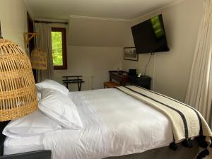 a bedroom with a white bed with a flat screen tv at Casa Molino Hotel Boutique & Restaurant Puerto Varas in Puerto Varas