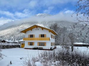 uma casa na neve com uma montanha ao fundo em Chalet Villa Alpen Lodge em Bichlbach