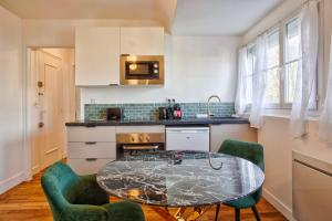 cocina con mesa de cristal y 2 sillas verdes en La Casa Mathilda Elegant & soothing cocoon, en Falaise