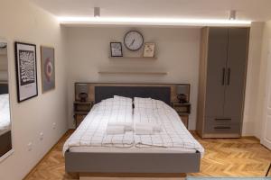 a bedroom with a bed and a clock on the wall at Apartmani Aleksandar in Vršac