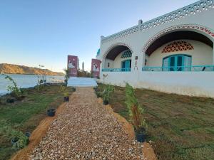 a building with plants in front of a body of water at Miskaa Nubian House in Naj‘ Tinjār
