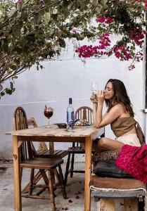een vrouw aan een tafel met een glas wijn bij Casa Brigita. Fortaleza in Fortaleza