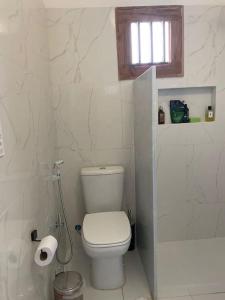 een witte badkamer met een toilet en een raam bij Casa Brigita. Fortaleza in Fortaleza