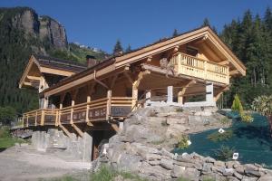 a large log cabin with a bridge over a river at Chalet le Nid independant mountain chalet in Morzine