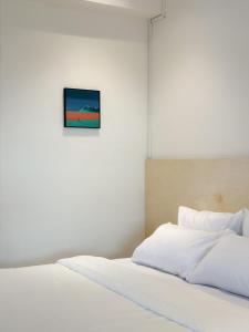 uma cama com lençóis brancos e uma foto na parede em Heritage Vacation Inn Balcony em Kuching