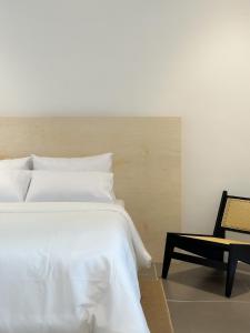 um quarto com uma cama branca e uma cadeira em Heritage Vacation Inn Balcony em Kuching