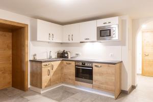 a kitchen with white cabinets and a microwave at Vitalhof am Kreischberg by ALPS RESORTS in Bodendorf