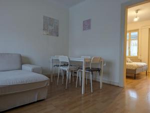 un soggiorno con tavolo, sedie e divano di Le Bâlois - appartement 2 chambres, salon, cuisine équipée, parking et wifi gratuit a Mulhouse
