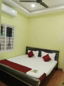 een slaapkamer met een groot bed met rode kussens bij gplushomestay in Madurai