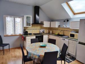 una cocina con mesa y sillas y una cocina con armarios blancos. en Gîte Baldersheim, 4 pièces, 5 personnes - FR-1-744-6 en Baldersheim