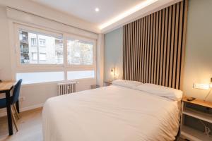 馬德里的住宿－I'M Room Suites Nuevos Ministerios - Bernabeu 'Digital Access'，一间卧室配有一张床、一张书桌和一个窗户。