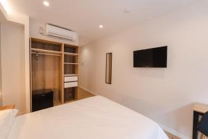 1 dormitorio con 1 cama blanca y TV en la pared en I'M Room Suites Nuevos Ministerios - Bernabeu 'Digital Access' en Madrid
