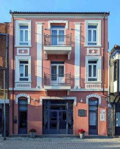 een roze gebouw met een balkon in een straat bij Melina Hotel - Central in Poligiros