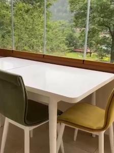 ウズンギョルにあるAygün Suites Hotel&Bungalow UZUNGÖLの白いテーブルと窓際の椅子2脚
