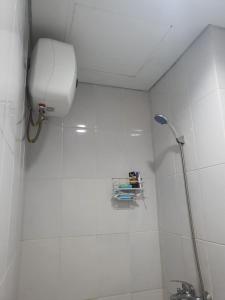 a white tiled bathroom with a toilet and a shower at Capital O 93490 Yubi Room Patraland in Bekasi