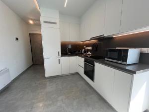 a kitchen with white cabinets and a microwave at Johnny's luxury getaway in Strovolos