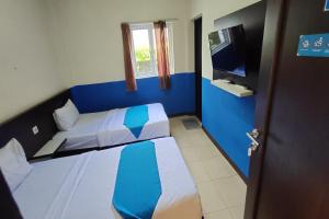 a small room with two beds and a television at OYO 93512 Umbuy Homestay in Rantau