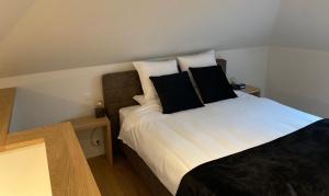 1 dormitorio con 1 cama con almohadas blancas y negras en 't pure genot, en Dilsen-Stokkem