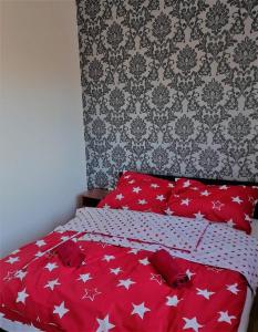 una cama roja con estrellas blancas en un dormitorio en Fehérvadász Vendégház, en Szombathely