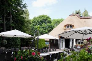 a group of tables with umbrellas in front of a building at Hotel Blauer Fasan in Wiesmoor