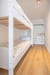 een slaapkamer met witte stapelbedden en een houten vloer bij Mosselbank 211 in Nieuwpoort