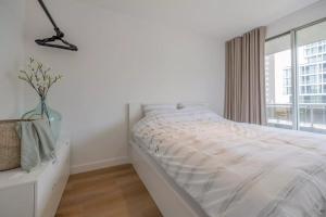 een witte slaapkamer met een bed en een raam bij Mosselbank 211 in Nieuwpoort