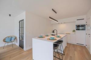 een witte keuken met een aanrecht en een wastafel bij Mosselbank 211 in Nieuwpoort +4 foto's
