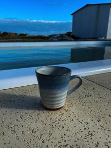 una taza de café sentada en una cornisa junto a una piscina en Rinkeby, en La Esmeralda