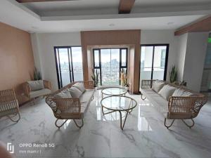a living room with a couch and chairs and windows at 19F One Katipunan Residence in Manila