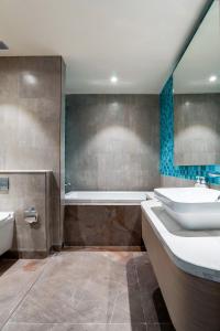 a bathroom with a tub and a sink and a bath tub at Holiday Inn Katra Vaishno Devi, an IHG Hotel in Katra