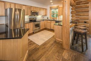 uma cozinha com armários de madeira e um frigorífico de aço inoxidável em Powder Ridge Cabin | 6 Chief Gull em Big Sky