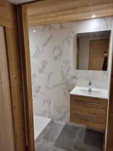 ein Bad mit einem Waschbecken und einem Spiegel in der Unterkunft Chalet Soleya in Le Grand-Bornand